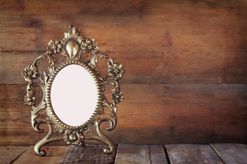 Antique blank victorian style frame on wooden table. vintage filtered image. template, ready to put photography
