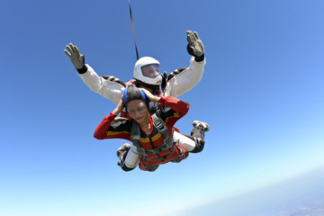 Fototapeta na wymiar Tandem jump. The girl with the instructor in freefall.