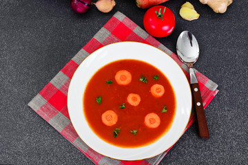 Carrot Tomato Soup in Plate. Behind lie on the soup ingredients,
