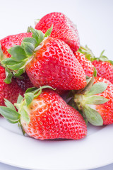 Strawberry red on a white plate and a white background, a bright image with contrast. side view, top. summer red berries. a series of color photographs