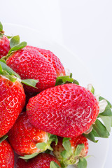 Strawberry red on a white plate and a white background, a bright image with contrast. side view, top. summer red berries. a series of color photographs