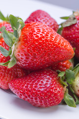 Strawberry red on a white plate and a white background, a bright image with contrast. side view, top. summer red berries.