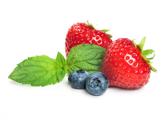 Strawberries, blueberries and mint leave, isolated on white.