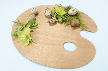Easter palette decoration with seven quail eggs and hellebore on a blue background