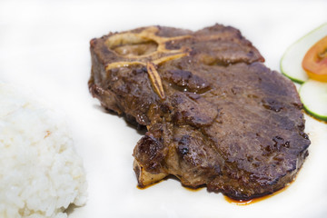 T Bone steak with rice and sauce on a white plate in a restaurant