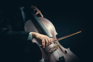 Man playing on cello on dark background