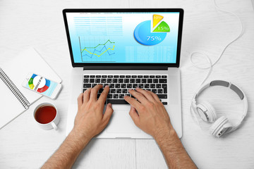 Man working with modern laptop, with scheme on screen. Top view