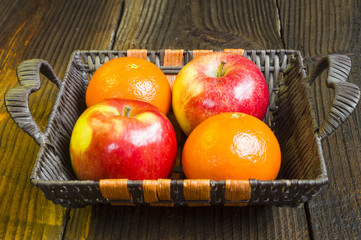 jabłka i pomarańcze wiklinowym koszyku