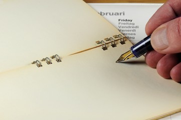 Vintage notebook with calendar and male hand writing with fountain pen.
