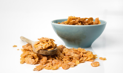 Oat flakes in bowl and wooden spoon on white background