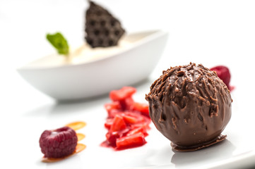 chocolate ball with ice cream and fruit on white plate, sweet dessert with chocolate, product photography for patisserie or restaurant