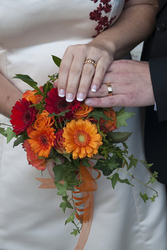 Hands and orange flowers with weddingrings. Händer och orangea blommor med vigselringar.