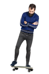 Naklejka premium Serious proud punker standing on longboard looking down with crossed arms. Full body length portrait isolated over white studio background. 