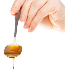 front view of hand holds metal spoon with honey