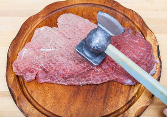 piece of veal is beating by meat mallet