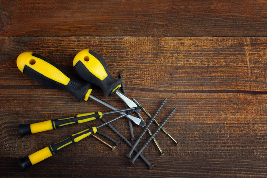 screwdriver and screws on a wooden brown table