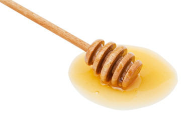 puddle of clear honey and wooden spoon close up