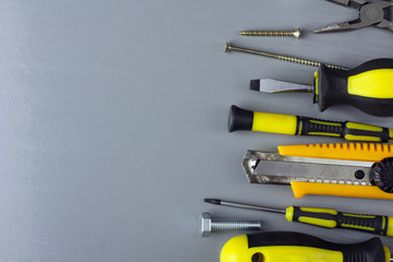 various forms of screws and screwdrivers and many other tools on grey wooden table