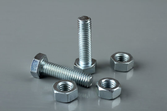 new bolts and nuts on a wooden table grey