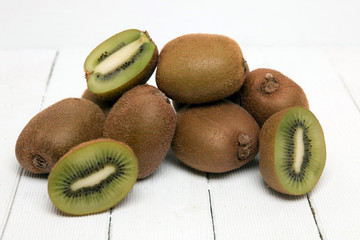 Tasty kiwi fruits isolated on a white wooden background.