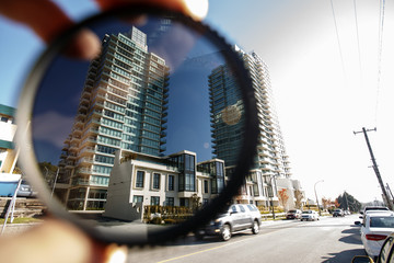 Polarizing filter held in front of a camera lens showing difference of polarized and unpolarized street scene. - obrazy, fototapety, plakaty
