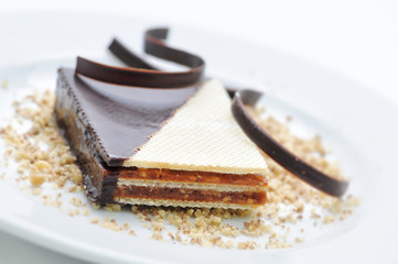 caramel cake with chocolate and nuts on white plate, sweet dessert, patisserie, shop