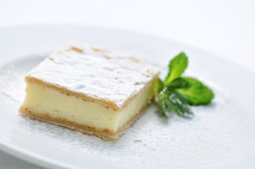 vanilla cream cake with sugar powder and mint leaf on white plate, sweet dessert or breakfast, patisserie, photography for shop