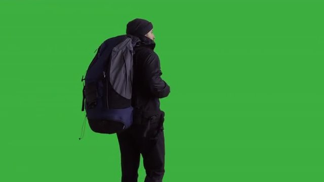 Young male hiker with a backpack looking into the distance - green screen. Prores 422HQ 4K UHD 60FPS slow motion shot. Shot with Blackmagic URSA Mini