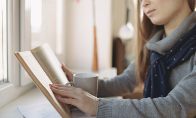 Educated woman reading artistic literature at home. Cropped photo.