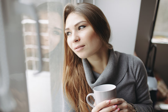 Attractive young woman sitting in a coffee shop at window