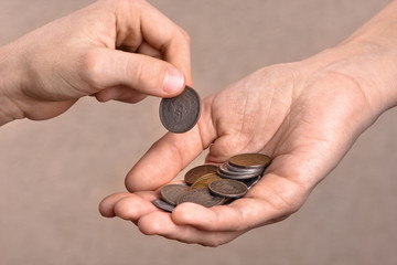 hand giving a coin to another person