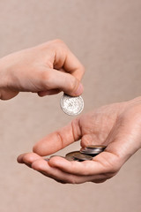 hand putting coins in the hand of another person