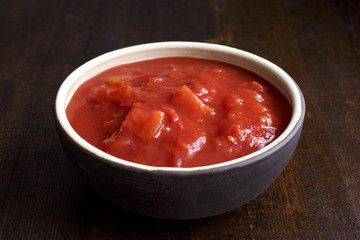 Brown ceramic bowl of chopped tinned tomatoes.