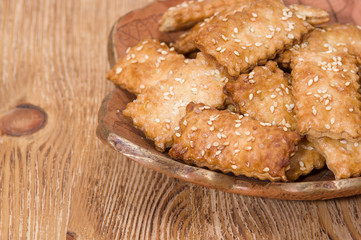 Cookies with sesame in the ceramic plate on the wooden background