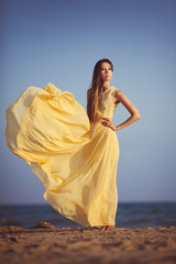 Fototapeta na wymiar Beautiful fashionable model on the beach in beautifu long dress