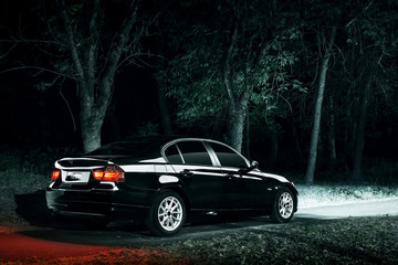 Black car stay in darkness forest at night