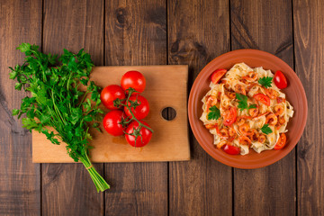 Fettuccine pasta with shrimp tomatoes and herbs. wooden background
