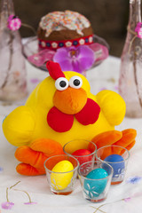 Fototapeta na wymiar Пасхальная композиция - игрушечная желтая курица с крашеными пасхальными яйцами разных цветов 