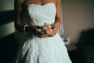 beautiful elegant bridesmaid putting on bracelet on the bride's hand on the background of a room in...