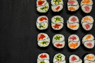 Rolls Yin-Yang with tuna and salmon and vegetable with cucumber and tomato on black background