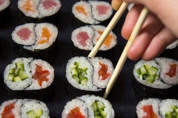 Rolls Yin-Yang with tuna and salmon and vegetable with cucumber and tomato on black background