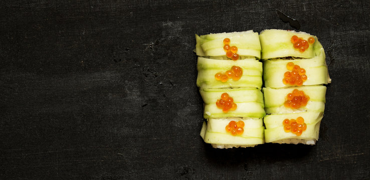 Rolls with zucchini and caviar on black background