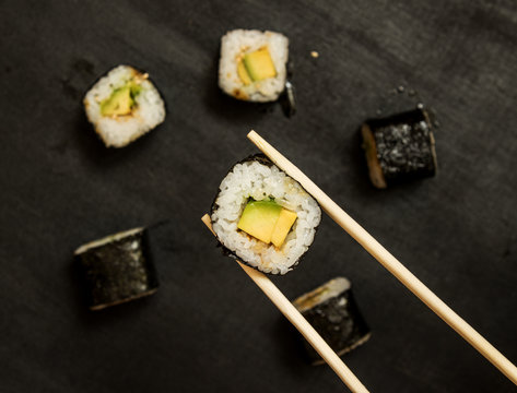Vegetable rolls with avocado and sauce on a black background