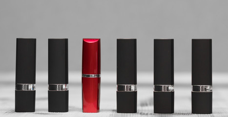 red lipstick and five black tubes on background
