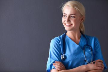 Young doctor woman with stethoscope isolated on gray background