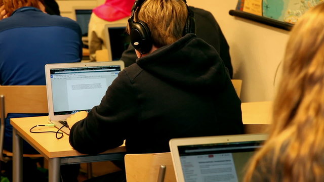 Students Inside a classroom using laptop for studying