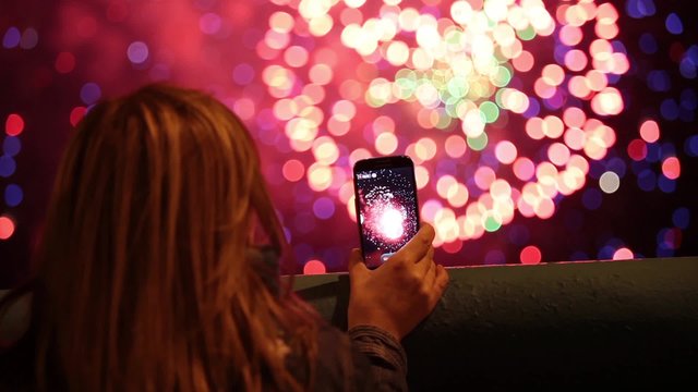 Girl using smartphone to record firework pyrotechnic show 