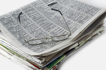 Оставленные очки лежат на пачке газет