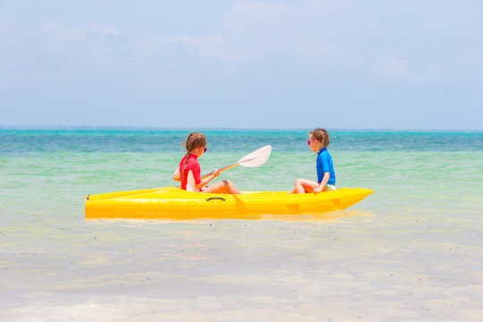 Little adorable girls enjoying kayaking on yellow kayak 