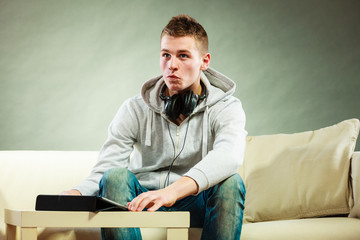 man with headphones sitting on couch with tablet